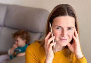 A volleyball mom on the phone organizing a group chat for the team parents.